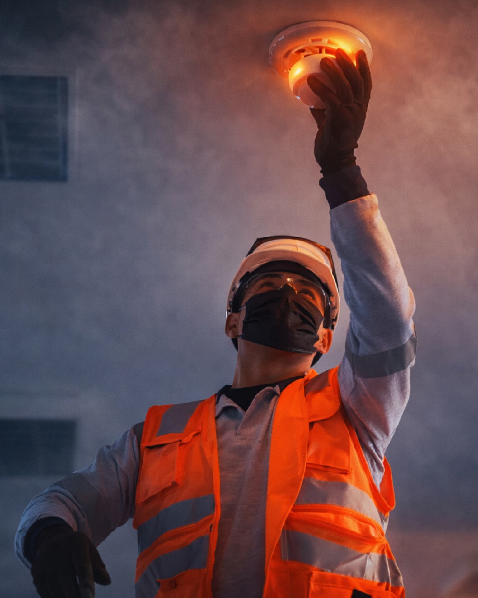 Técnico de Alvic instalando un sensor de humo en un entorno con humo